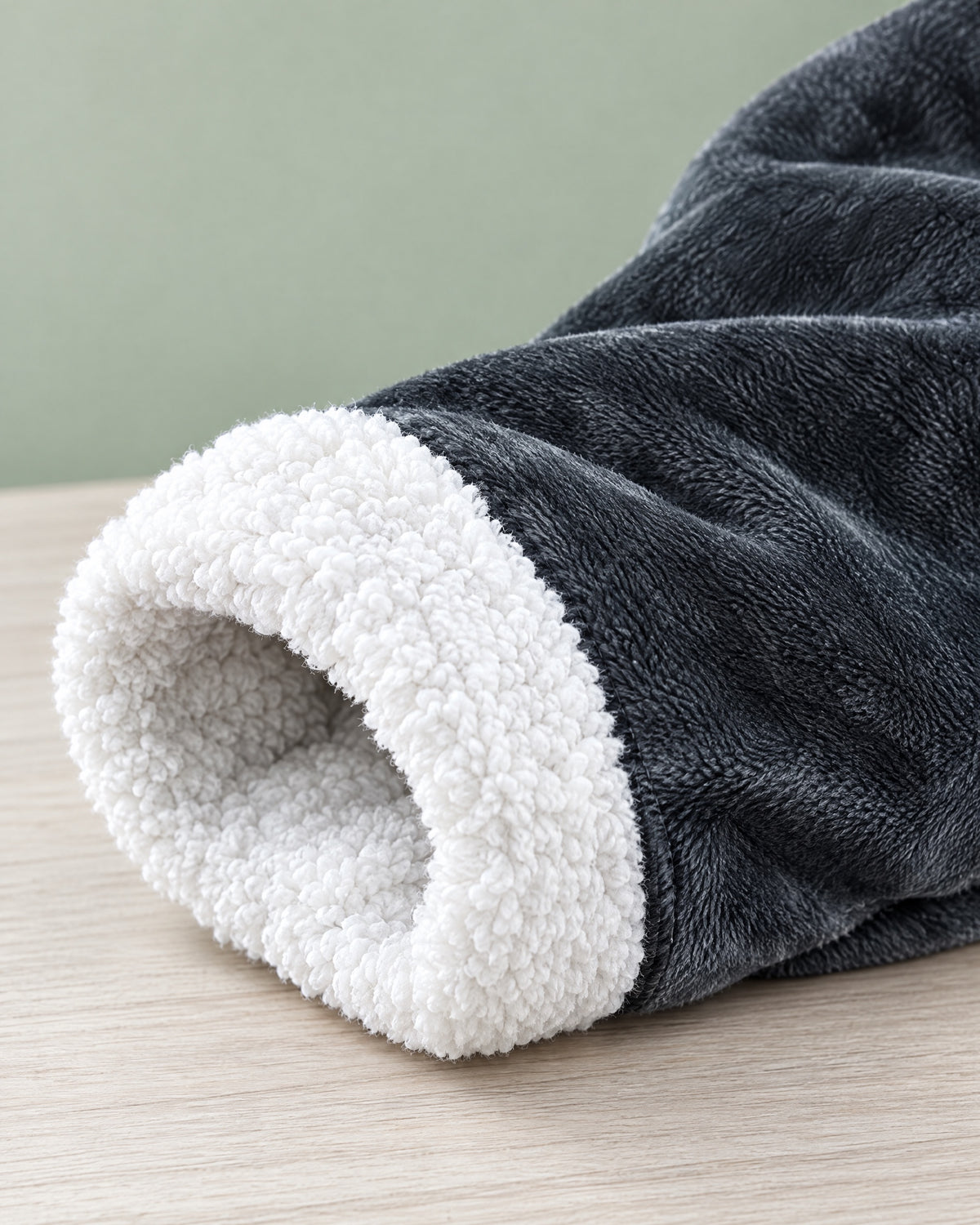 Close view of a sleeve of the Ember heated blanket showing charcoal flannel and white sherpa cuff
