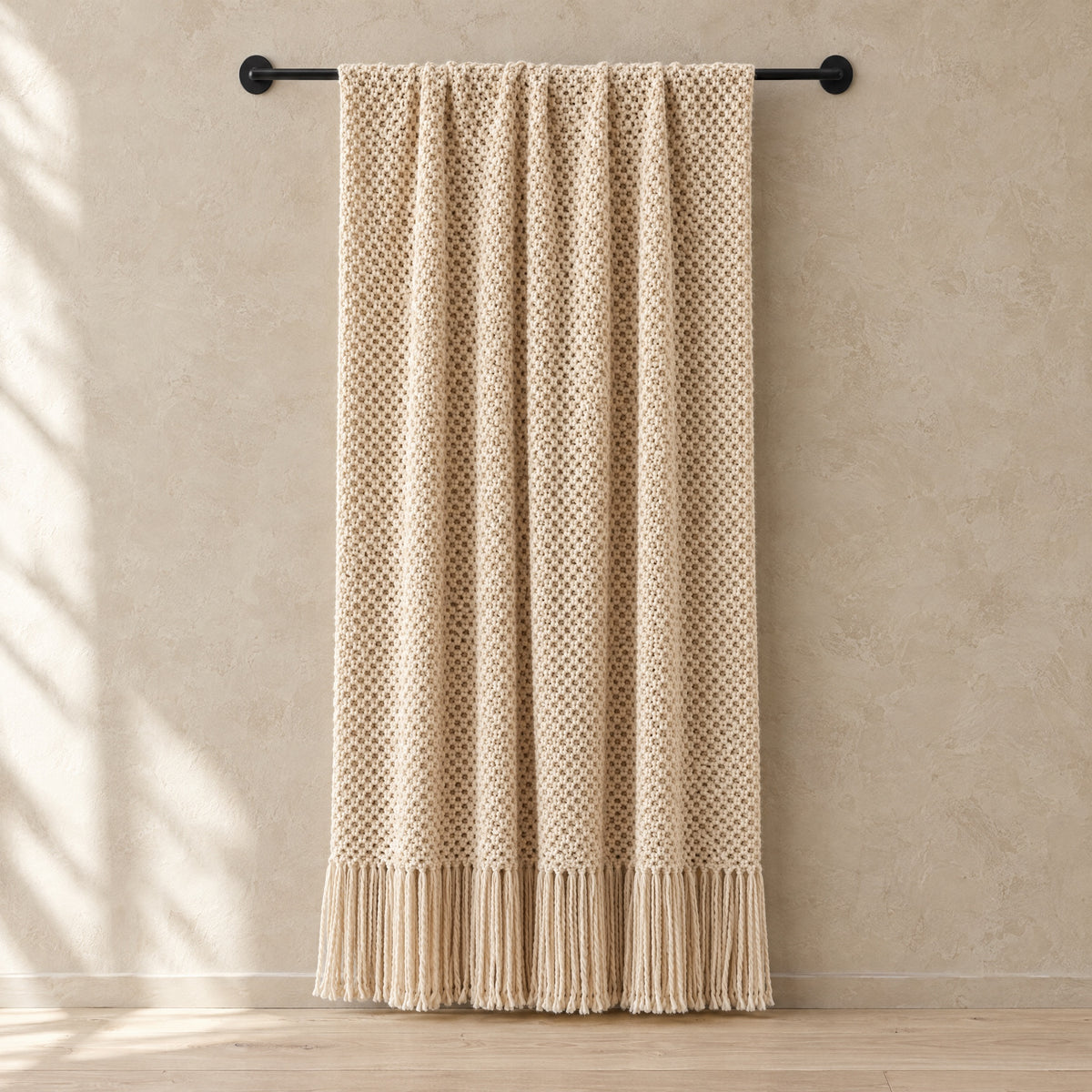 Fenn Knitted Tassel Throw hanging from a wall rail