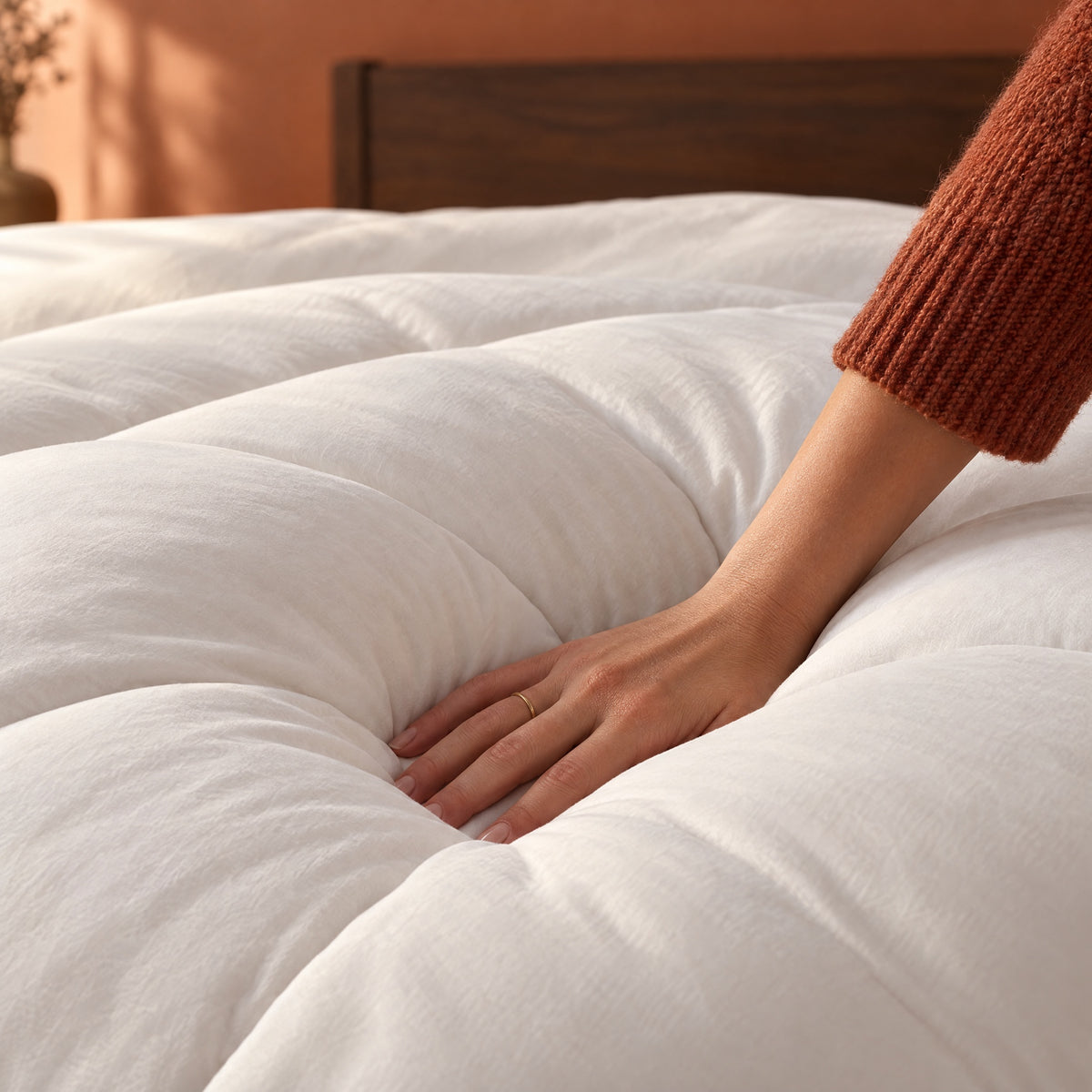 Hand pressing into the white Nimbus Comforter to show its depth